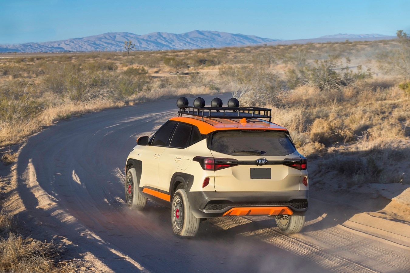 Kia Seltos 2021 X-Line beige et orange, sur route semi-désertique, vue de dos, un peu de côté